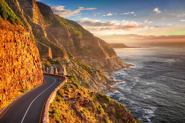 Atlantic-edge driving in Cape Town beneath cliffs, cloud, and blue distance